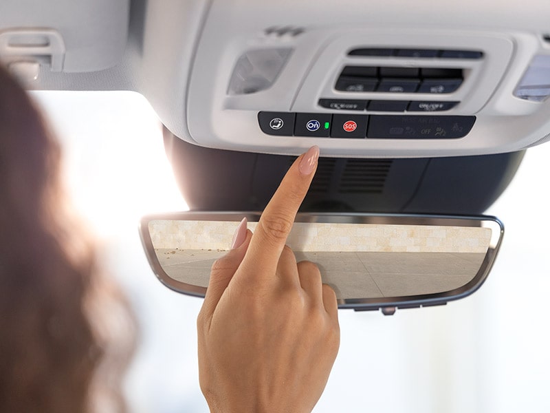 Close-up view of a Person Reaching to Press the OnStar Button in a 2025 Buick Envision Compact SUV.