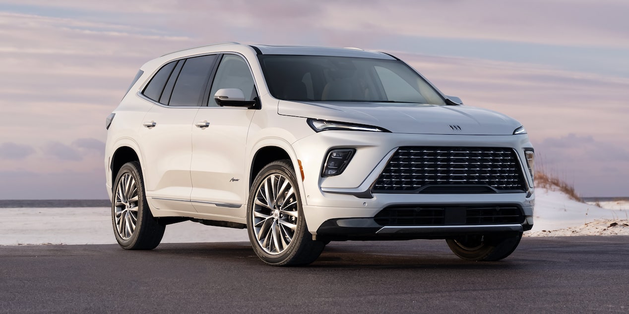 Front-side view of the 2025 Buick Enclave parked near a body of water during sunset.