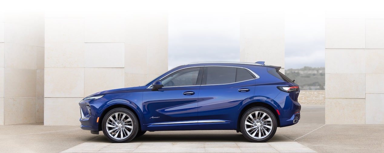 Front Three-Quarters View of a 2025 Buick Envision Compact SUV Parked in Front of a Building.