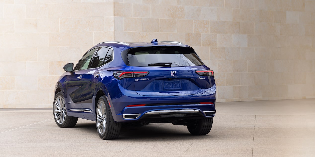 Back-side view of the 2025 Buick Envision Avenir Compact Luxury SUV parked near a white Concrete Building.