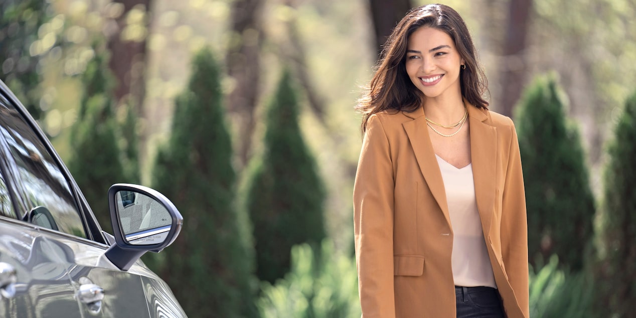 Une femme sourit à côté du Buick Envision 2024.